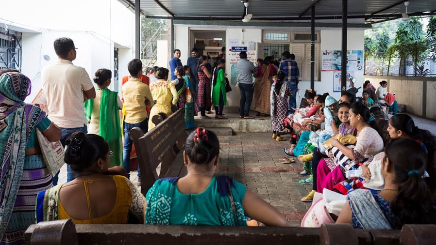 Parents, children and babies waiting at TB medical clinic, India.