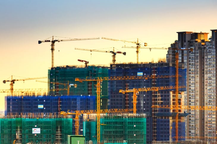 Construction site cityscape with high-rise cranes and half built buildings against a setting sun sky