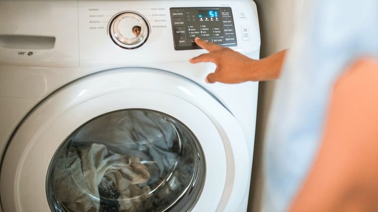 User switches on front loading washing machine full of clothes