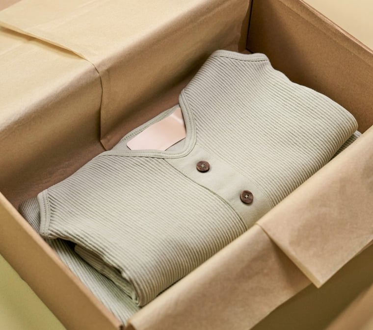 Sustainable clothing folded into a sustainable cardboard box lined with unbleached tissue paper