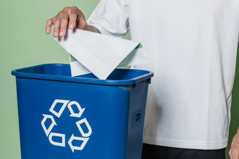 Man recycles paper in recycling bin